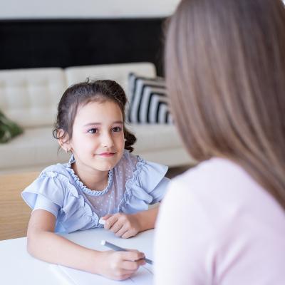 Young girl looking at woman across table